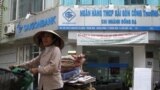 Một người bán hàng rong đi ngang qua một chi nhánh Saigon Commercial Bank, Hà Nội, 6 tháng 12, 2011. Hình minh hoạ.