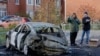 Russian law enforcement officers inspect a burnt-out car in the courtyard of residential buildings following a drone attack in the village of Sofyino, Moscow region, on November 10, 2024.